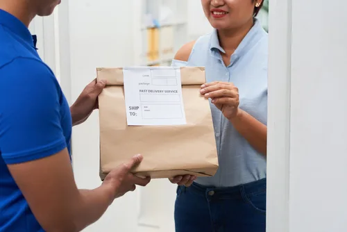 Pessoa recebendo encomenda em casa — entrega FedEx na porta